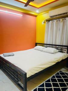 a bed in a room with an orange and yellow wall at House Of Green Flag VIP ROAD Baguiati Kolkata in kolkata