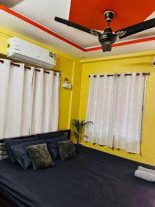 a bedroom with a bed with white curtains and a ceiling fan at House Of Green Flag VIP ROAD Baguiati Kolkata in kolkata