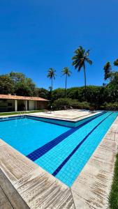a blue swimming pool with palm trees in the background at Mango Village Paracuru CE in Paracuru
