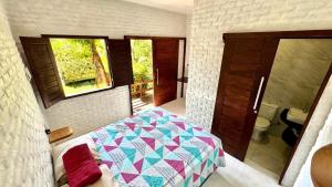a bedroom with a bed and a bathroom with a window at Mango Village Paracuru CE in Paracuru