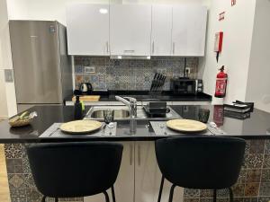 a kitchen with a sink and two black chairs at Frades house in Câmara de Lobos