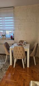 a dining room table and chairs with a white table and a window at Apartman Tajna in Sremčica
