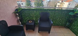 a balcony with two chairs and a clock on a table at Apartman Tajna in Sremčica