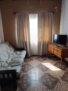 a room with a couch and a television and a dresser at Los Patitos Bungalows in Gualeguaychú
