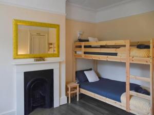 a bedroom with two bunk beds and a fireplace at North Cottage in Lowestoft