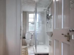 a white bathroom with a toilet and a shower at North Cottage in Lowestoft +8 photos