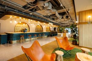 a lobby with orange chairs and a bar at HOTEL METROPOLITAN OIMACHI TRACKS Tokyo in Tokyo