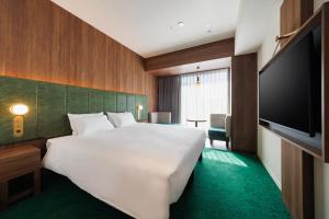 a hotel room with a large bed and a flat screen tv at HOTEL METROPOLITAN OIMACHI TRACKS Tokyo in Tokyo