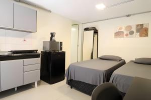 a room with two beds and a microwave and a kitchen at Studio VII - Completo -Centro de Jundiaí in Jundiaí +4 photos