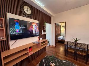 a living room with a large television and a clock on the wall at The RM Homestay in Baclayon