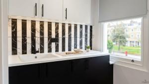 a white kitchen with a sink and a window at Clapton Station Luxury Studios near Central London in London