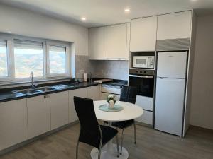 a kitchen with a white table and a white refrigerator at Panorama Douro House in Armamar