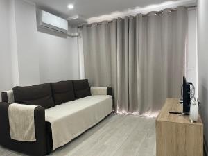 a living room with a black couch and a television at Olimpus Apart Leasure in Costa de Adeje