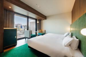 a hotel room with a bed and a large window at HOTEL METROPOLITAN OIMACHI TRACKS Tokyo in Tokyo