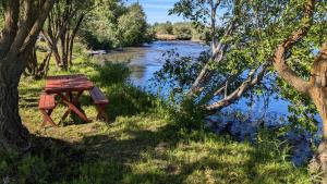a wooden picnic table sitting next to a river at Henrys Fork Suites Suite One in Saint Anthony