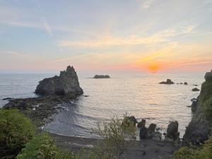 a sunset over the ocean with rocks in the water at Apartamentos Rurales LLeguera in Llanes