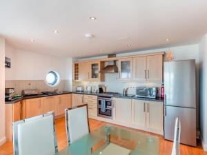 a kitchen with wooden cabinets and a stainless steel refrigerator at 10 Horizons in Newquay
