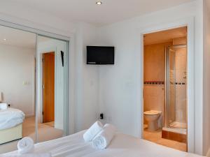 a white room with a bed and a bathroom at 10 Horizons in Newquay