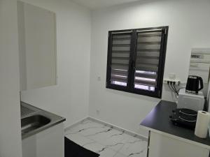 a white kitchen with a window and a counter at Cozy renovated studio Comfort practicality in Bourgoin
