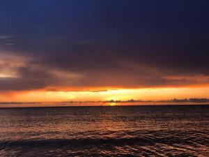 a sunset over a body of water with the sun setting at Caba La Union Gulfside Cottage C2 in Caba