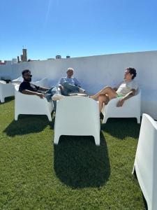a group of people sitting in white chairs on the grass at Samps Hostel in Lisbon