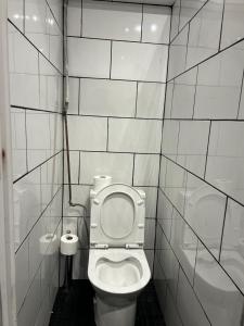 a bathroom with a toilet in a white tiled wall at Samps Hostel in Lisbon