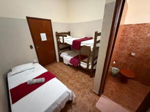 a small room with two beds and a shower at Ferrari's Hotell in Miguelópolis +3 photos