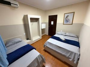 a bedroom with two beds and a mirror at Ferrari's Hotell in Miguelópolis