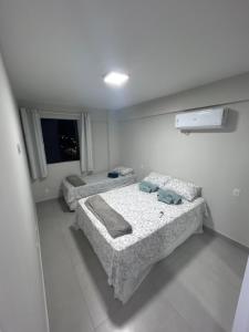 two beds in a white room with a window at Refúgio em Intermares, 250m do Mar com piscina in Cabedelo +39 photos