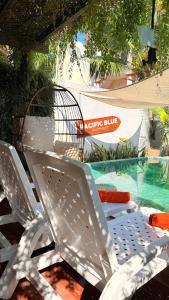two white chairs sitting next to a swimming pool at Pacific Blue in Monterrico