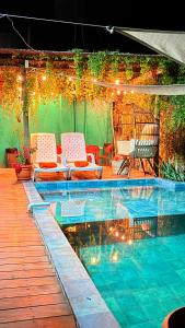 a patio with chairs and a swimming pool with lights at Pacific Blue in Monterrico