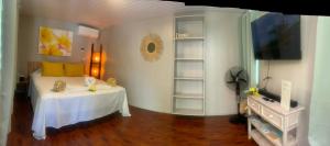 ein Zimmer mit einem Bett, einem Tisch und einem Fernseher in der Unterkunft Rangiroa Tiny House in Avatoru