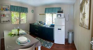 eine Küche mit Kühlschrank, Tisch und Spüle in der Unterkunft Rangiroa Tiny House in Avatoru