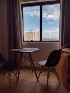 a table and two chairs in a room with a window at MN Gotado Hotel Flat Guarulhos Aeroporto in Guarulhos