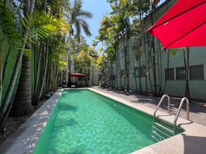 a swimming pool with a red umbrella next to a building at Suites Galván centro Colima, alberca, Wifi, parking in Colima