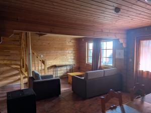a living room with two couches and a wooden wall at Chalé 24 in Penhas da Saúde +1 photo