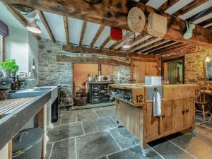 a large kitchen with a counter and a stone wall at Ynywsen Dairy Flat in Nantgaredig