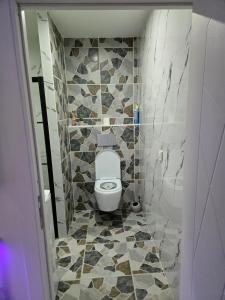 a bathroom with a toilet and a tiled floor at Studio modern climatise in Bourgoin