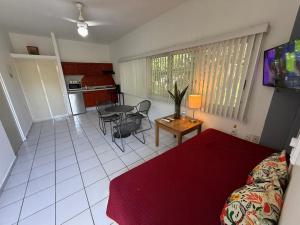a living room with a red bed and a kitchen at Suites Galván centro Colima, alberca, Wifi, parking in Colima