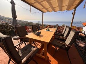 a wooden table with chairs and an umbrella on a balcony at Casa das Flores Funchal in Funchal