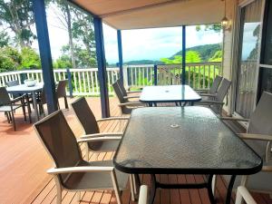 a patio with tables and chairs on a deck at Cloud 9 Eagle Heights - Cliff-Top, Ocean Sunrise, VIP Retreat in Mount Tamborine