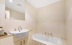 a white bathroom with a sink and a tub at Ground level unit with private courtyard in Melton