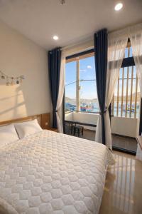 a bedroom with a bed and a large window at Đầm Nại Hotel in Ninh Hải