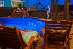 a pool with two chairs and a table and a glass of wine at Blizzard's Lighthouse home in Port Isabel