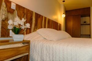 a bedroom with a bed with a vase of white flowers at Hotel Tres Reinas in Xicotepec de Juárez +4 photos