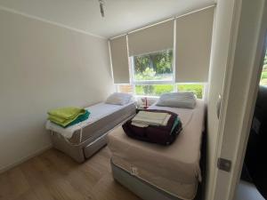 a small room with two beds and a window at Departamento en papudo in Papudo