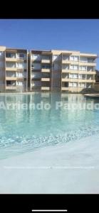 a large swimming pool in front of a building at Departamento en papudo in Papudo