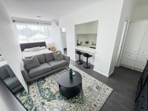 a living room with a couch and a table at Clean Bright Studio Apartment - Walkable Location in Melbourne
