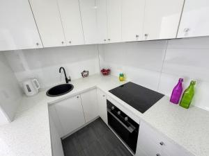 a white kitchen with a sink and a stove at Clean Bright Studio Apartment - Walkable Location in Melbourne +1 photo