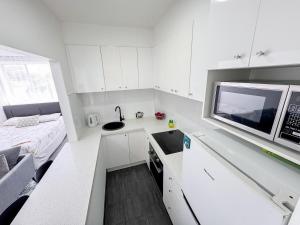 a small white kitchen with a sink and a microwave at Clean Bright Studio Apartment - Walkable Location in Melbourne